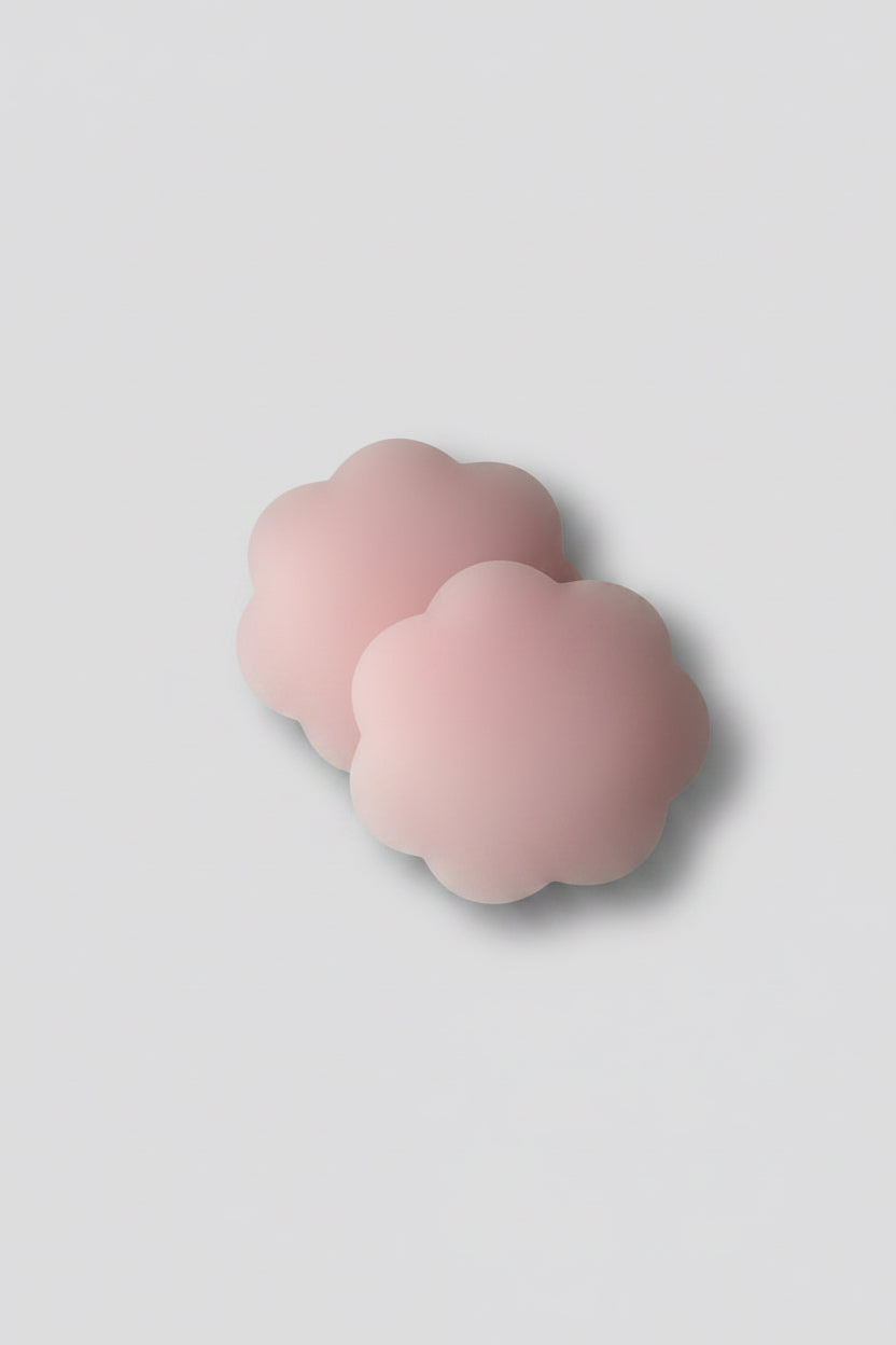 A pair of pink silicone breast adhesives on a light gray background