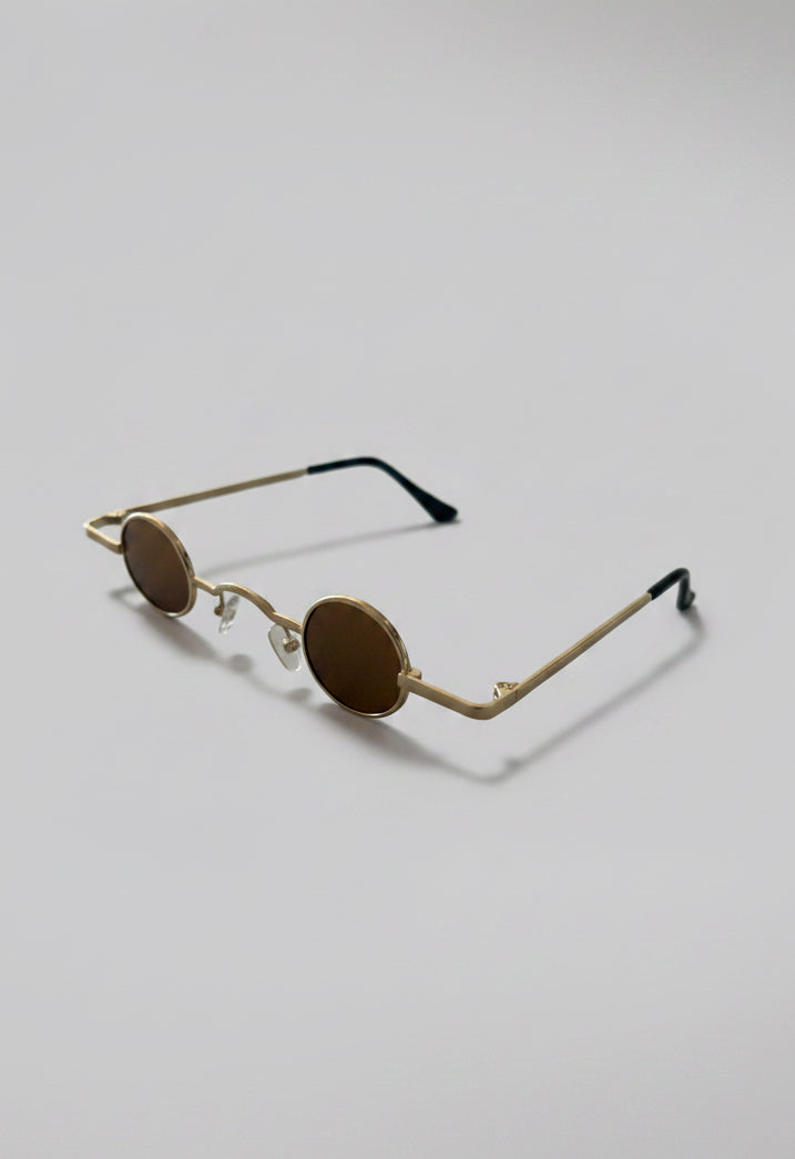 Micro round sunglasses with gold frame and brown lenses on a light gray background