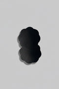 A pair of black breast adhesives on a light gray background