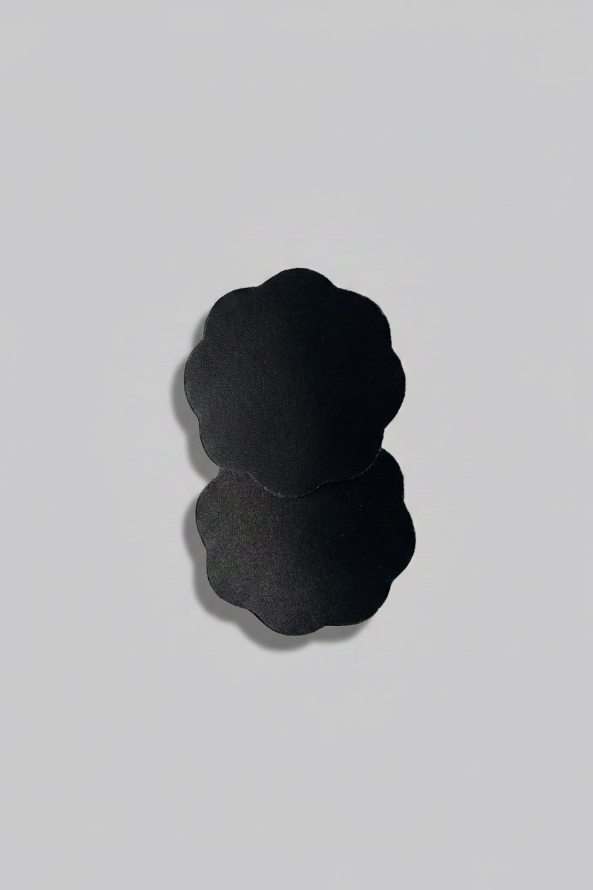 A pair of black breast adhesives on a light gray background