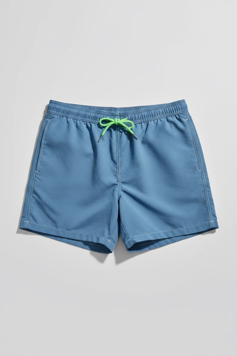 A pair of men's casual swim shorts in a dusty medium blue color, featuring an elastic waistband and a bright lime green drawstring, laid flat on a light gray background.