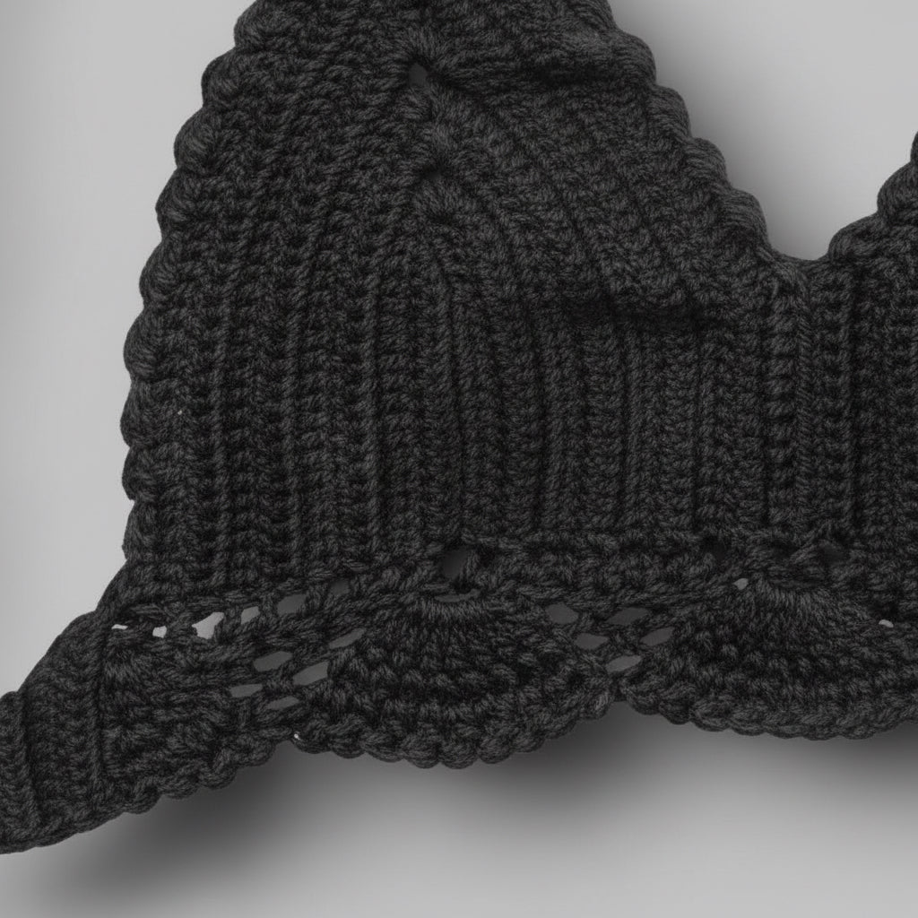 Close up of black knitted bikini top on a light grey background