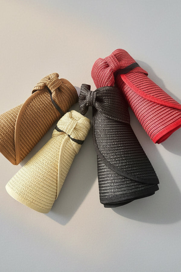 Set of folded straw brim hats in brown, beige, black, and red on a grey background