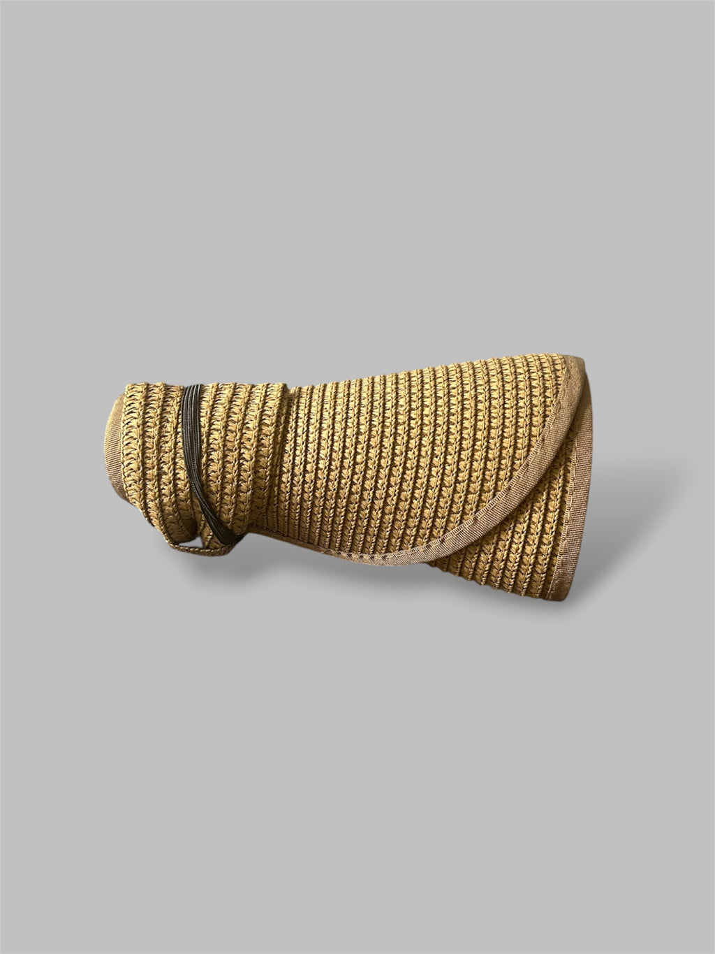 Brown straw brim hat rolled up on a gray background