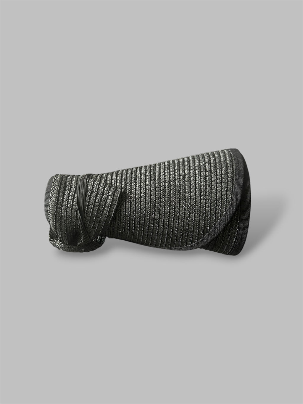 Black straw brim hat rolled up on a gray background