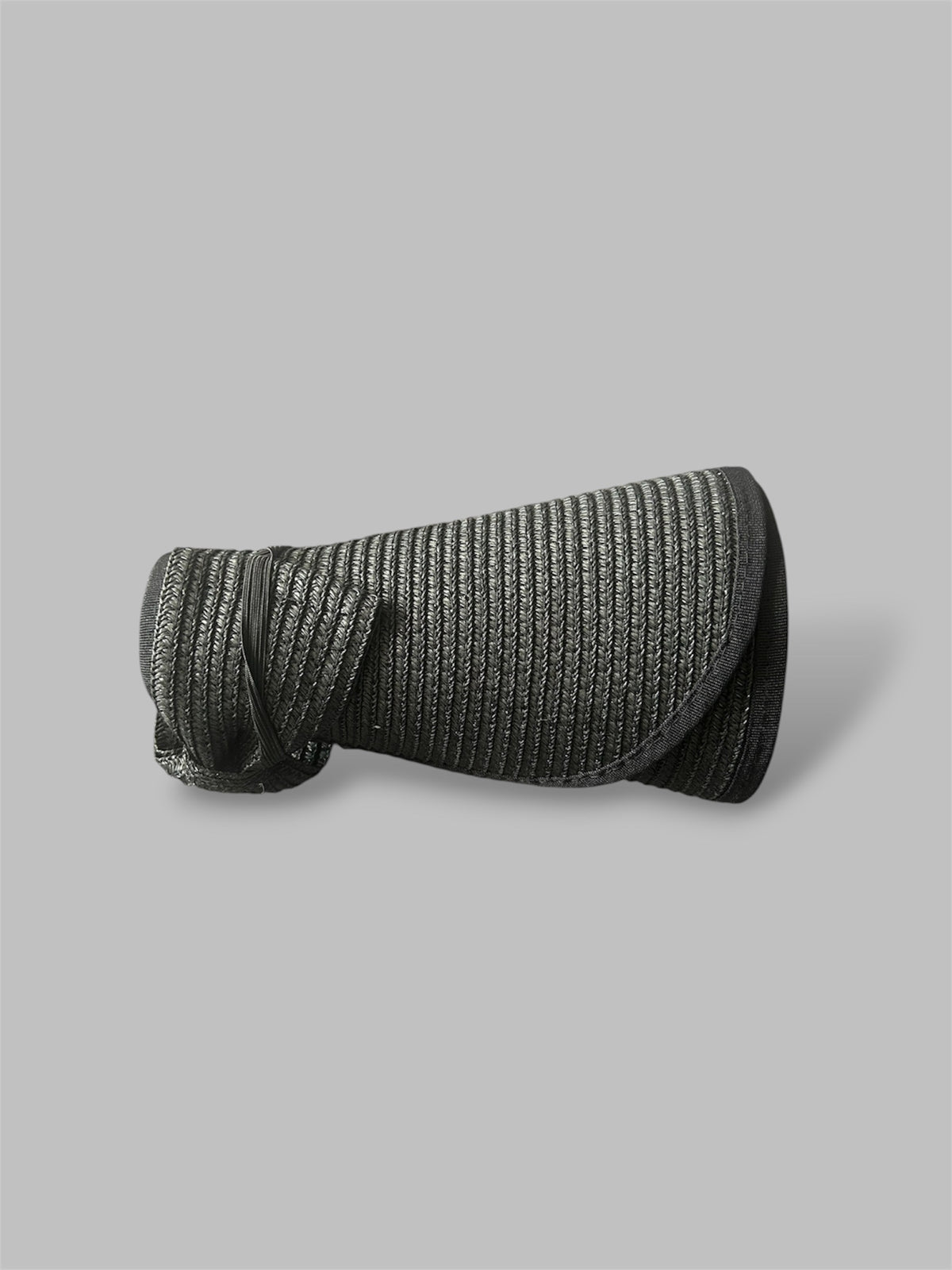 Black straw brim hat rolled up on a gray background