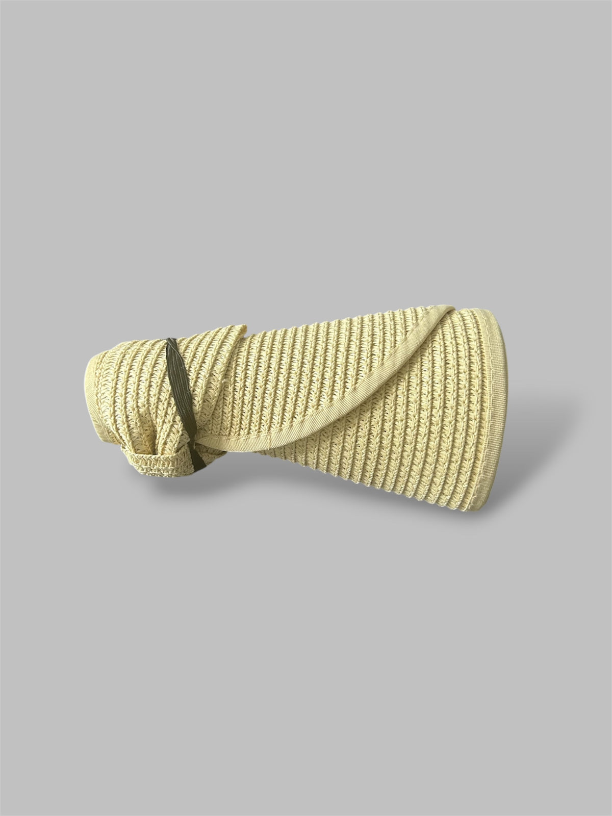 Beige straw brim hat rolled up on a gray background