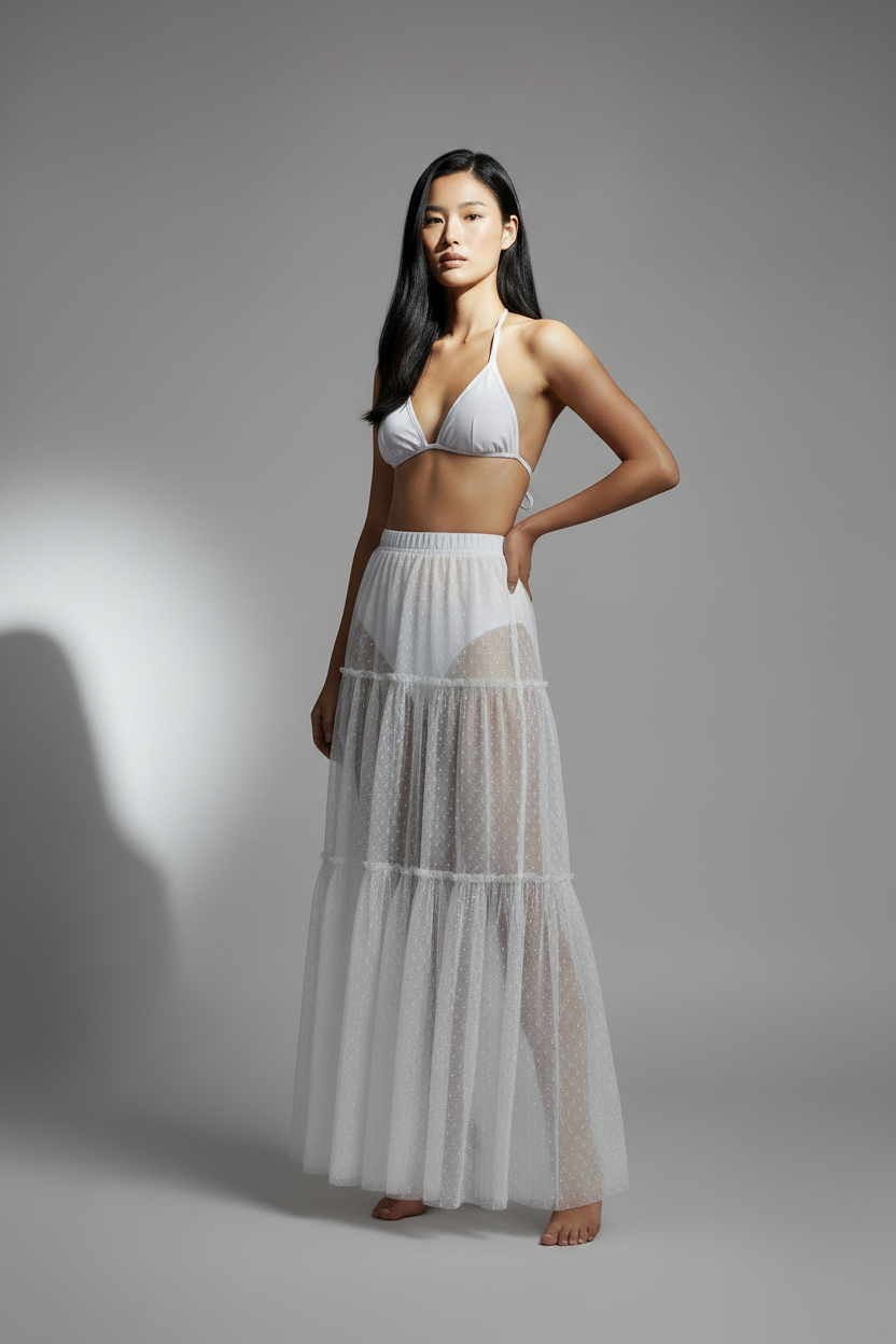 Woman wearing a white bikini and long mesh skirt against a beige background