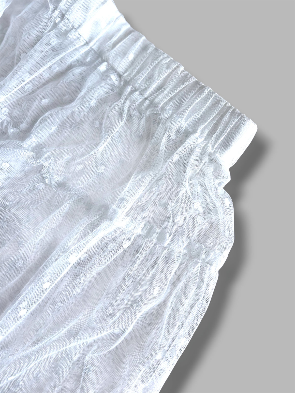Close-up of a white sheer maxi skirt with gray background