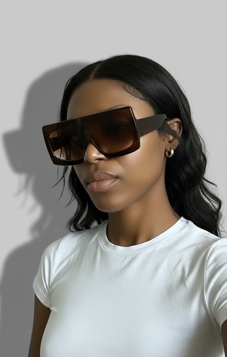 Model wearing brown bold sunglasses and a white baby tee